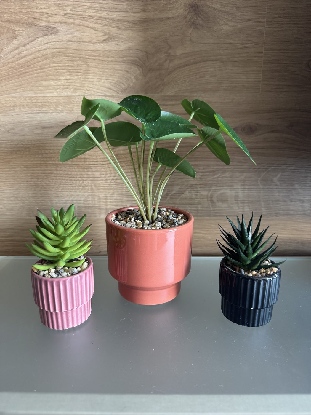 Três plantas artificiais em vasos de cerâmica