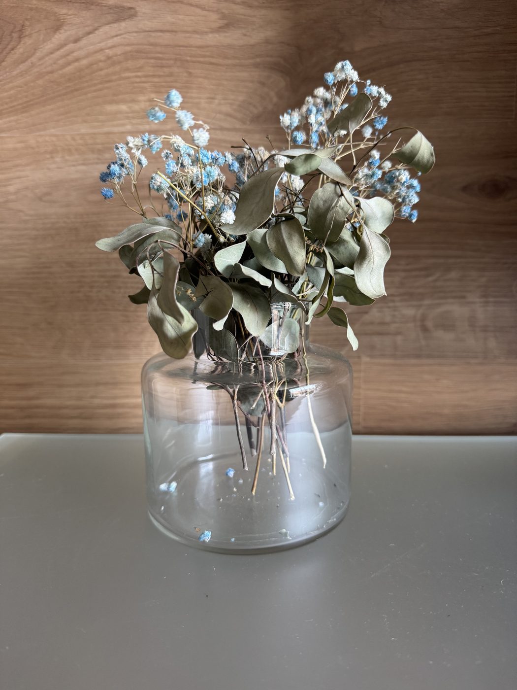 Vaso de vidro grande com eucalipto e flores secas azuis